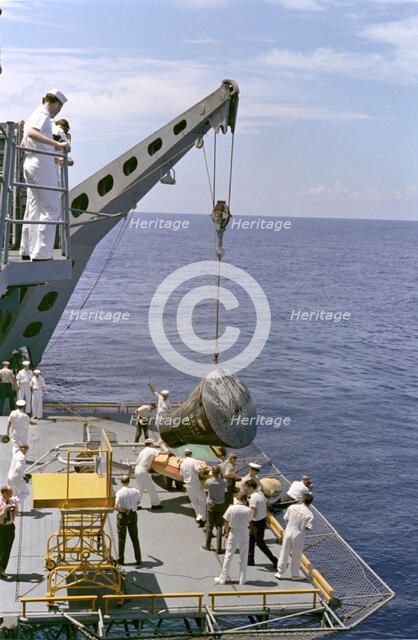 Gemini 5 capsule hoisted onboard recovery ship, 1965. Creator: NASA.