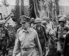 General Douglas MacArthur Walking With American Troops Through Jungle in the Pacific Campaign, 1943. Creator: British Pathe Ltd
