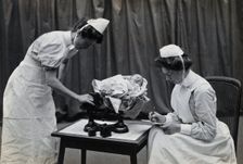 General Lying In Hospital, York Road, Lambeth: nurses weighing a baby, 1906 Creator: Unknown