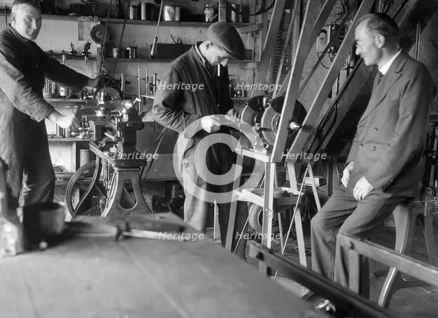 Geoffrey Baker with two other men in a workshop. Artist: Bill Brunell.