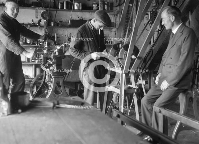 Geoffrey Baker with two other men in a workshop. Artist: Bill Brunell.