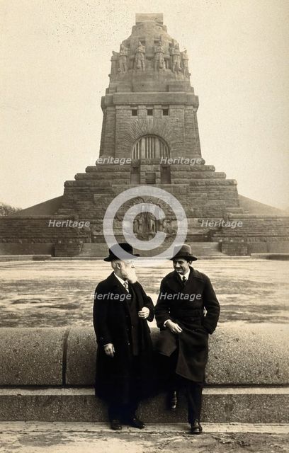 Georg Sticker and an unknown companion, in front of a war memorial (?). Creator: Unknown.