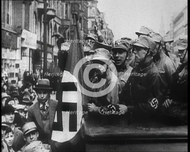 German Civilians and Men in Nazi Uniforms With a Nazi Flag, 1933. Creator: British Pathe Ltd.