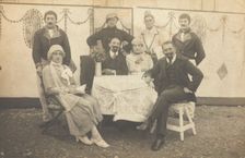 German soldiers, some in drag, pose round a table at a concert party, (between 1910 and 1919?). Creator: Unknown