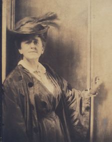 Gertrude Ka¨sebier, wearing feathered hat, standing, facing front, half-length portrait, c1900. Creator: Adolph de Meyer