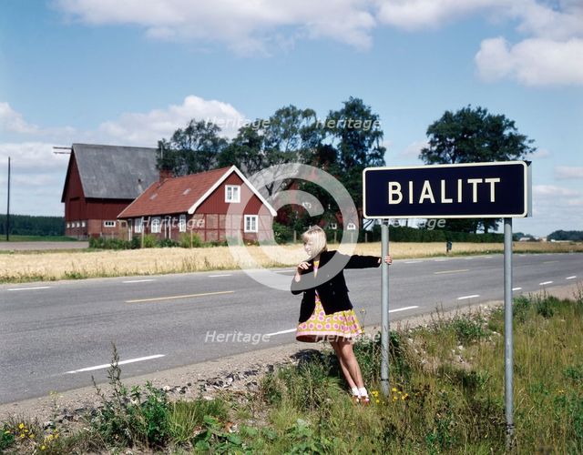 Girl by a road sign for Bialitt, Sweden. Creator: Torkel Lindeberg.
