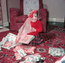 Girl opening her Christmas presents, c1955. Creator: Arthur Charles Kirby Ware