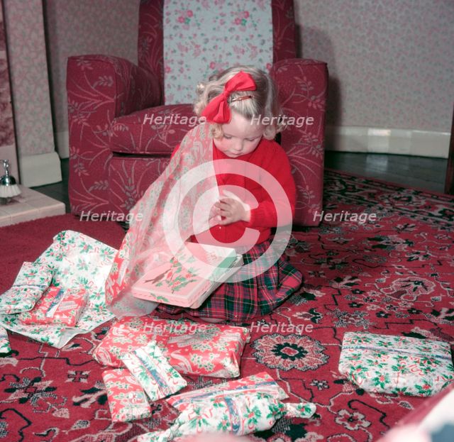 Girl opening her Christmas presents, c1955.  Creator: Arthur Charles Kirby Ware.