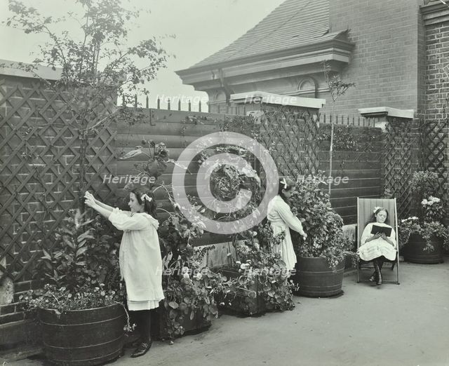 Girls gardening and reading in a roof top garden, White Lion Street School, London, 1912. Artist: Unknown.