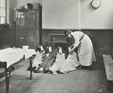 Girls drying their hair by the fire after a bath, Chaucer Cleansing Station, London, 1911