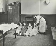 Girls drying their hair by the fire after a bath, Chaucer Cleansing Station, London, 1911