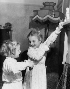 Girls hanging up Christmas stockings, c1955. Creator: Arthur Charles Kirby Ware