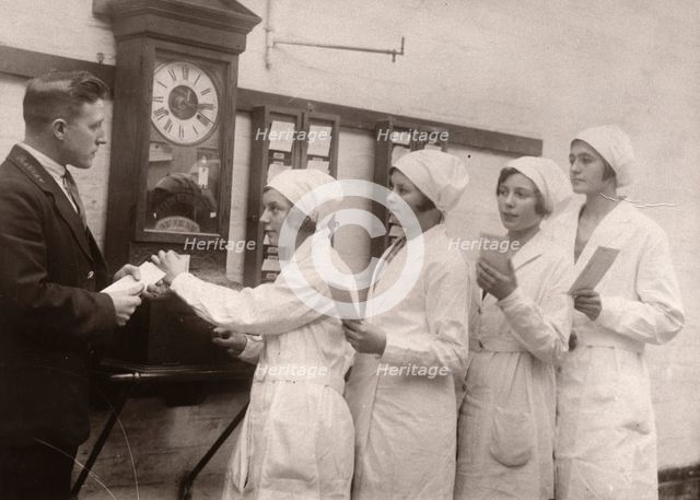 Girls queue at the Clocking-In machine, Rowntree factory, York, Yorkshire, 1933. Artist: Unknown