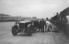 GL Baker's 5954 cc Minerva undergoing a rear wheel change at Brooklands. Artist: Bill Brunell