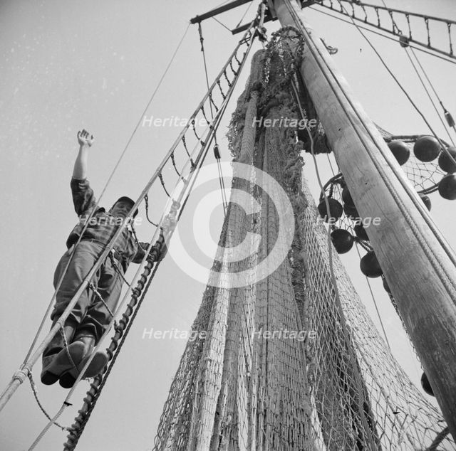 Gloucester fisherman standing in the rigging of a New England fishing boat, New York, 1943. Creator: Gordon Parks.