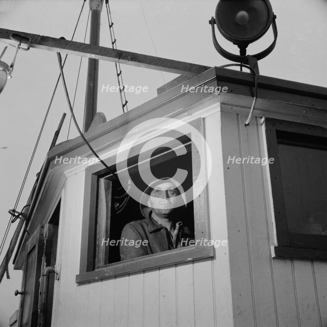 Gloucester, Massachusetts. Lorenzo Scola maneuvers ship during mackerel chase, 1943. Creator: Gordon Parks.
