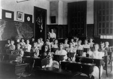Grade school children posed in classroom, with teacher standing in back..., Washington DC, (1899?). Creator: Frances Benjamin Johnston
