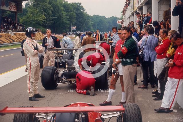 Graham Hill watches Mechanics working on a car, French Grand Prix, Rouen, 1968. Artist: Unknown