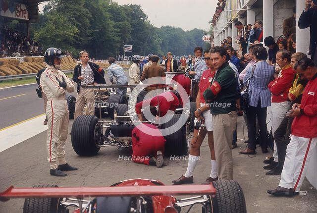 Graham Hill watches Mechanics working on a car, French Grand Prix, Rouen, 1968. Artist: Unknown