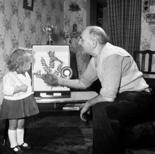 Grandfather and child with a prize winning caged bird, Horden, County Durham, 1963. Creator: Michael Walters