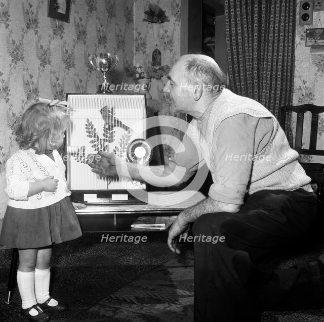 Grandfather and child with a prize winning caged bird, Horden, County Durham, 1963. Creator: Michael Walters.