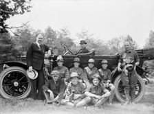 Group of Boy Scouts Posed with Dog And Three Men in Front of An Automobile, between 1914 and 1917. Creator: Harris & Ewing
