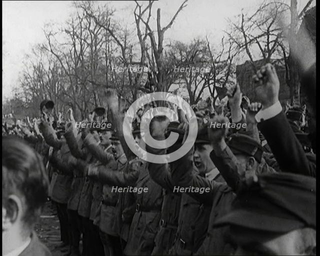 Group of Male Civilians Standing and Cheering With Their Fists Raised in the Air, 1924. Creator: British Pathe Ltd.