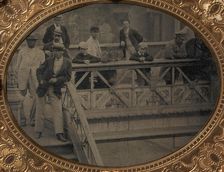 Group of Men and Boys Standing Along the Railing of the Fulton Street Bridge, 1866-68. Creator: Unknown