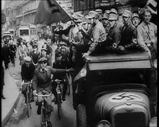 Group of Men in Nazi Uniform Driving Down the Road as Civilians Watch, 1933. Creator: British Pathe Ltd