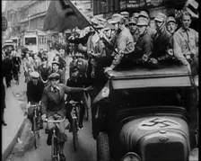 Group of Men in Nazi Uniform Driving Down the Road as Civilians Watch, 1933. Creator: British Pathe Ltd