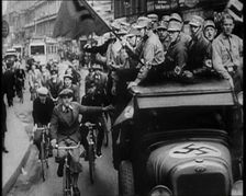Group of Men in Nazi Uniform Driving Down the Road as Civilians Watch, 1933. Creator: British Pathe Ltd