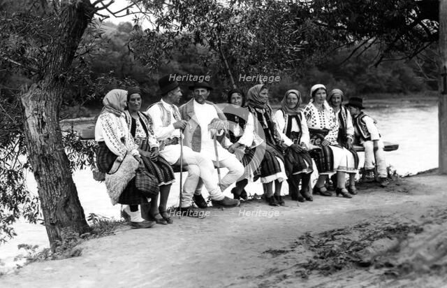 Group of people seated on a bench, Bistrita Valley, Moldavia, north-east Romania, c1920-c1945. Artist: Adolph Chevalier