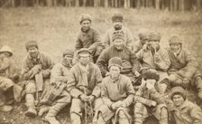 Group portrait of convicts seated in a field, between 1880 and 1886. Creator: Unknown