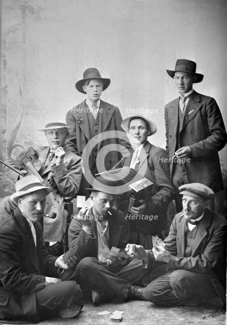 Group photo of men with musical instruments and playing cards, 1915.  Creator: Unknown.