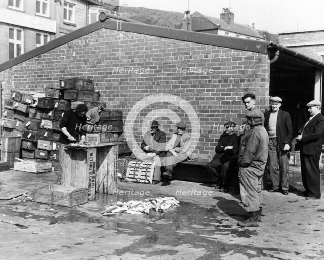 Gutting fish outside a warehouse in Whitby, North Yorkshire, 1959. Artist: Unknown