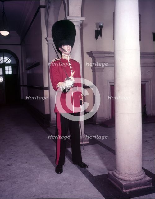 Guards officer in full dress uniform with bearskin on and sword drawn, London,  Creator: Arthur Charles Kirby Ware.