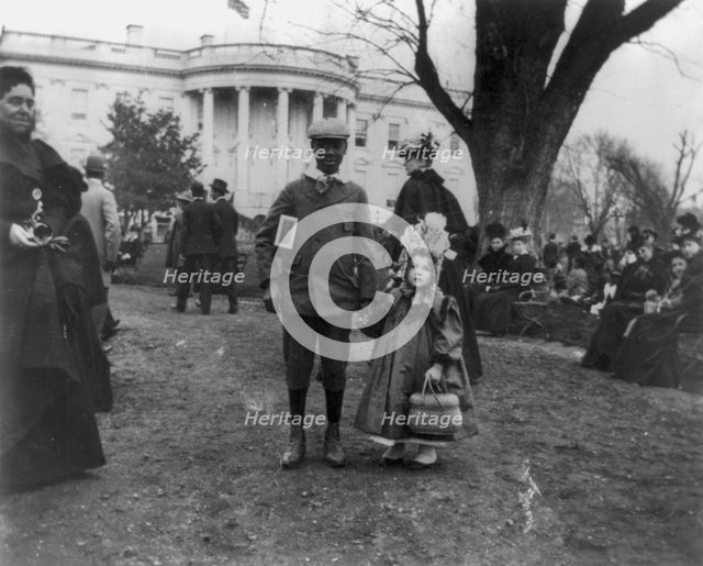 D.C. Wash. - White House - Negro boy holding hand of small white girl during Easter egg roll, 1898. Creator: Frances Benjamin Johnston.