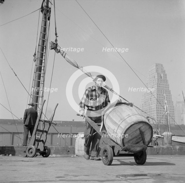 Dock stevedore at the Fulton fish market moving a barrel of codfish, New York, 1943. Creator: Gordon Parks.