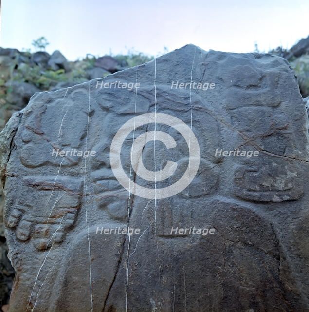 Detail of a sculptural relief on a rock representing a man with a large earring, at his left the …