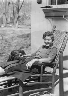 DeLamar, Alice, Miss, with dog, seated outdoors, between 1927 and 1942. Creator: Arnold Genthe