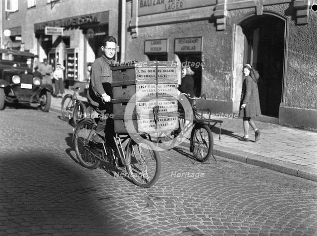 Delivery boy with bread boxes from the Lisa Öhman Bakery, Stockholm, Sweden, 10th October 1942. Creator: Karl Sandels.
