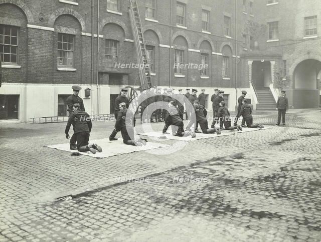 Demonstrating how to pick up an unconscious person, London Fire Brigade Headquarters, London, 1910. Artist: Unknown.