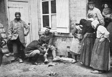 Derriere L'ennemi refoule; Un major soignant un allemand blesse que des villageois..., 1915 (1924). Creator: Unknown