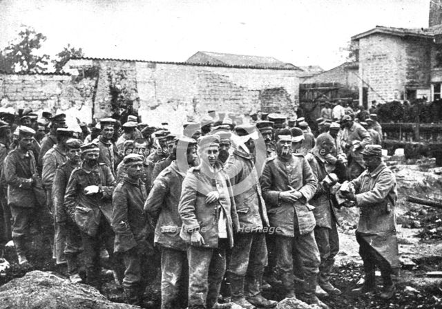 'Derriere L'ennemi refoule; Nos territoriaux distribuent du pain a des prisonniers...1915 (1924). Creator: Unknown.