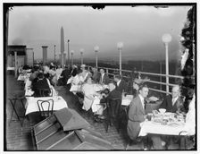 Dining on rooftop; Washington monument in background, between 1910 and 1920. Creator: Harris & Ewing