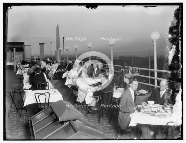Dining on rooftop; Washington monument in background, between 1910 and 1920. Creator: Harris & Ewing.