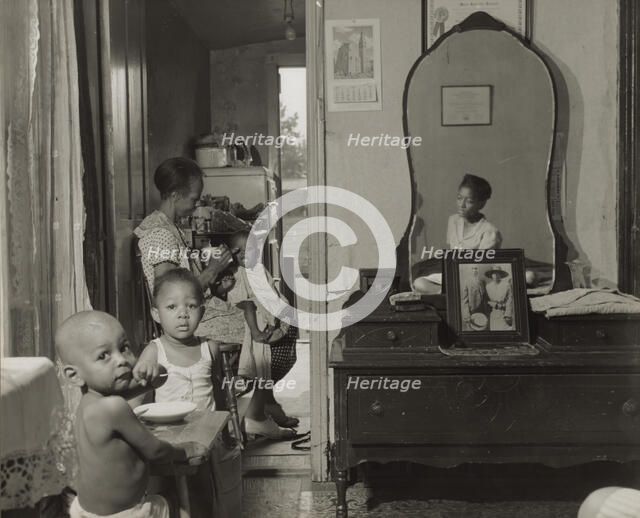 Dinner time at the home of Mrs. Ella Watson, a government charwoman, Washington, D.C., 1942. Creator: Gordon Parks.