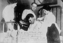 Dr. James F. Grant, ship's surgeon, fixing up Gordon G. Davidson, survivor of EMPRESS OF..., 1914. Creator: Bain News Service