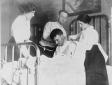 Dr. James F Grant, ship's surgeon, fixing up Gordan G Davidson, survivor of EMPRESS OF..., 1914. Creator: Bain News Service