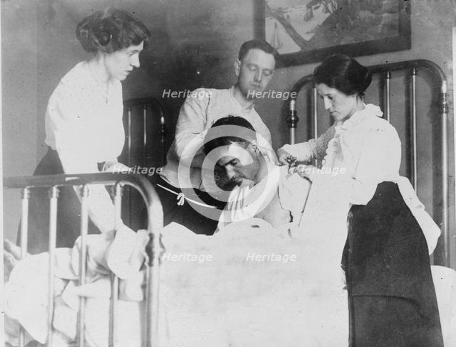 Dr. James F Grant, ship's surgeon, fixing up Gordan G Davidson, survivor of EMPRESS OF..., 1914. Creator: Bain News Service.